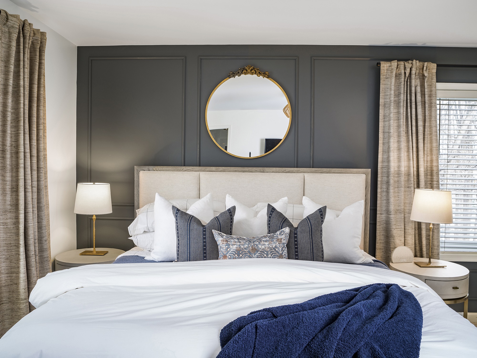 bedroom with neutral bed and accent wall with moulding